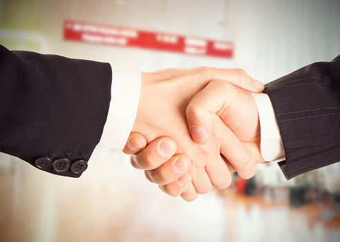 Close-up partial view of businespeople shaking hands on black
