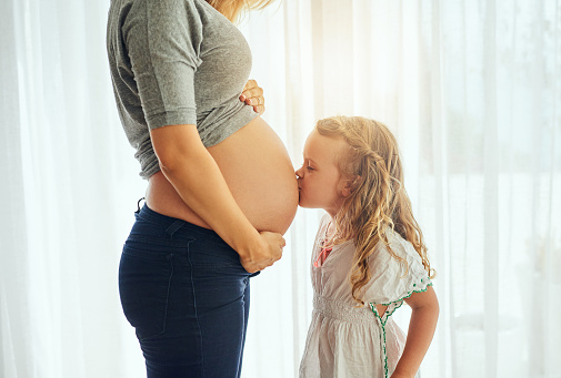 Cropped shot of a little girl kiss her mother's pregnant belly