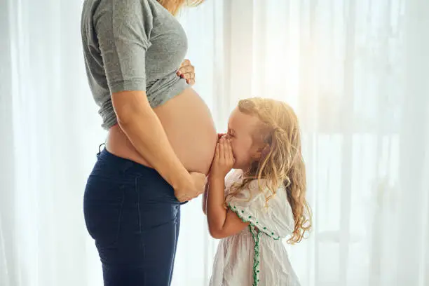 Cropped shot of a little girl whispering to her mother's pregnant belly