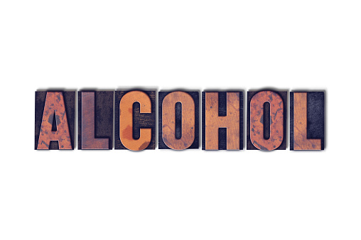 The word Alcohol concept and theme written in vintage wooden letterpress type on a white background.