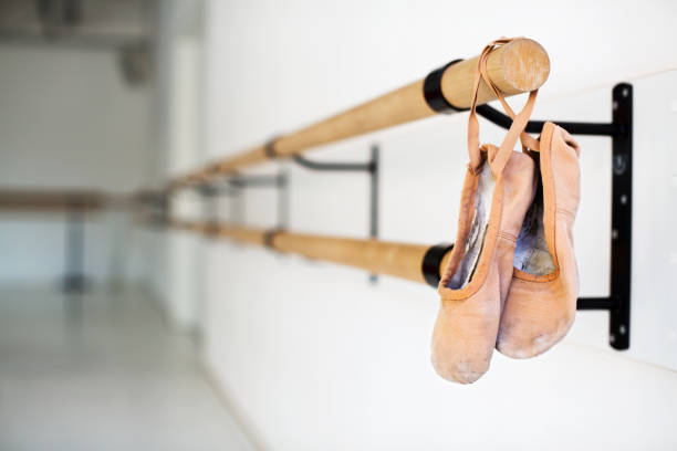 Ballet shoes hanging on wooden barre in studio Ballet shoes hanging on wooden barre. Pair of ballet slippers hanging from handrail. It is in dance studio. ballerina shoes stock pictures, royalty-free photos & images