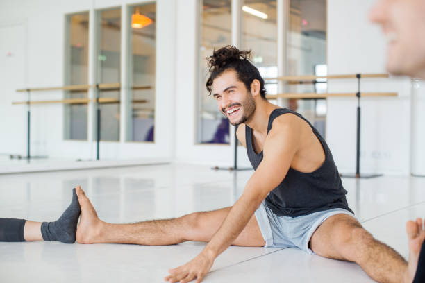 smiling man doing stretching in ballet studio - the splits ethnic women exercising imagens e fotografias de stock