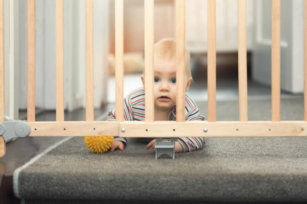 istock baby playing with ball behind safety gates 815137270