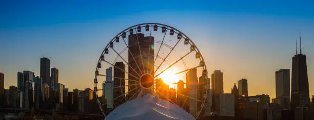 The sun sets behind the Navy Pier Ferris Wheel in Chicago, Illinois.