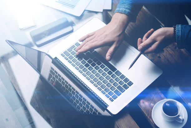 istock Businessman working with laptop at office,typing on keyboard.Modern notebook, cup of black coffee and smartphone on the wooden table.Horizontal, bokeh effects. 815166570