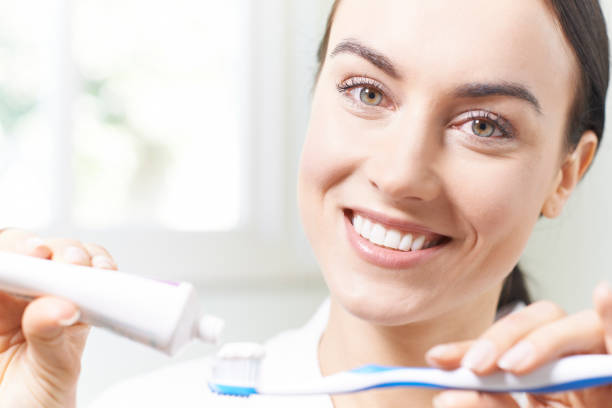 istock Woman Squeezing Toothpaste Onto Tootbrush In Bathroom 815180496