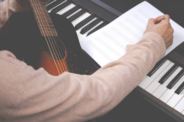 male songwriter writing song on blank music sheet stock photo