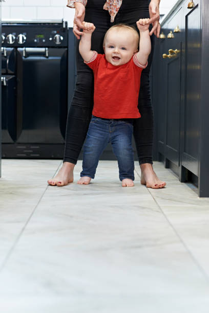 istock Mother Helping Baby Son To Walk In Kitchen 815185646