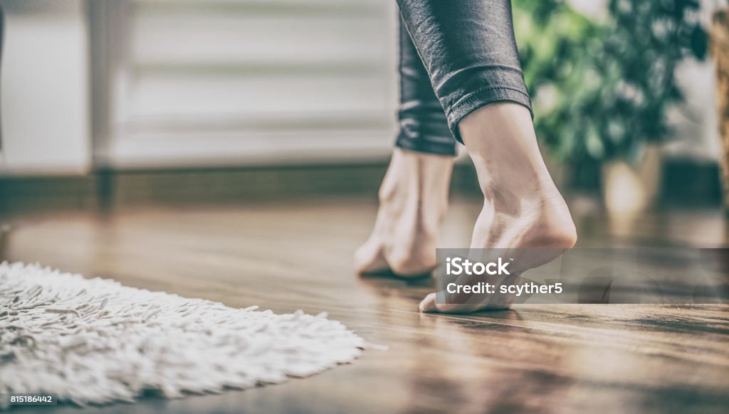 Warm floor - the concept of floor heating and wooden panels. Floor heating. Young woman walking in the house on the warm floor. Gently walked the wooden panels. Adult Stock Photo