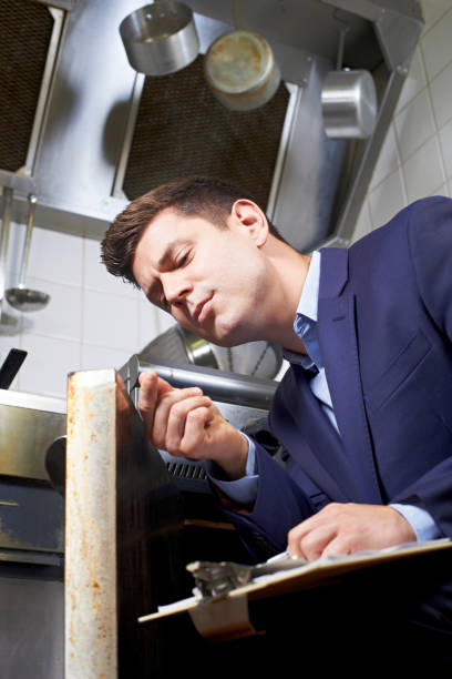 istock Health Inspector Looking At Oven In Commercial Kitchen 815196262