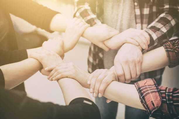 A group of young people hold strong hands. A group of young people hold strong hands. Sign of trust and teamwork. arm in arm stock pictures, royalty-free photos & images