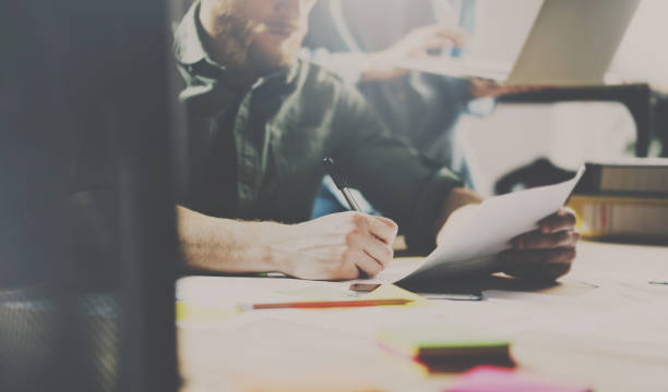 istock Concept of teamwork process.Young coworker working with new startup project in modern office. Contemporary notebook on wood table. Horizontal, color filter effect. 815196530
