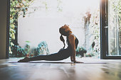 Portrait of gorgeous young woman practicing yoga indoor. Beautiful girl practice cobra asana in class.Calmness and relax, female happiness.Horizontal, blurred background.Visual effects.