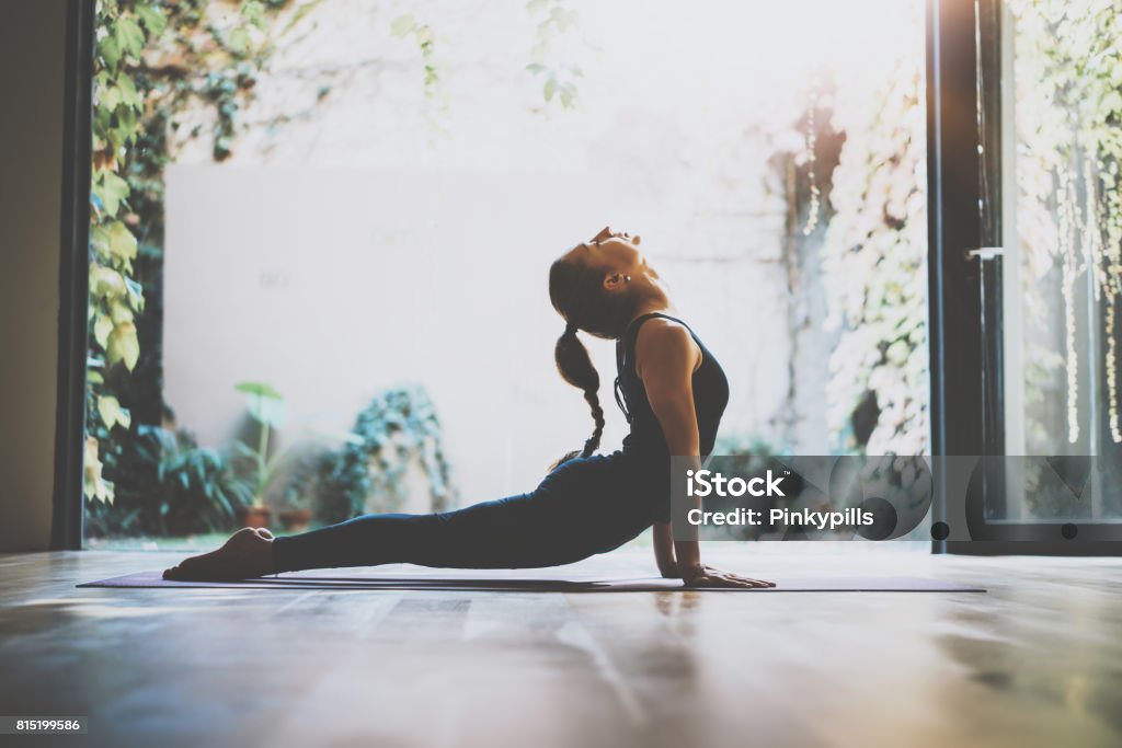 Portrait of gorgeous young woman practicing yoga indoor. Beautiful girl practice cobra asana in class.Calmness and relax, female happiness.Horizontal, blurred background.Visual effects. Portrait of gorgeous young woman practicing yoga indoor. Beautiful girl practice cobra asana in class.Calmness and relax, female happiness.Horizontal, blurred background.Visual effects Yoga Stock Photo