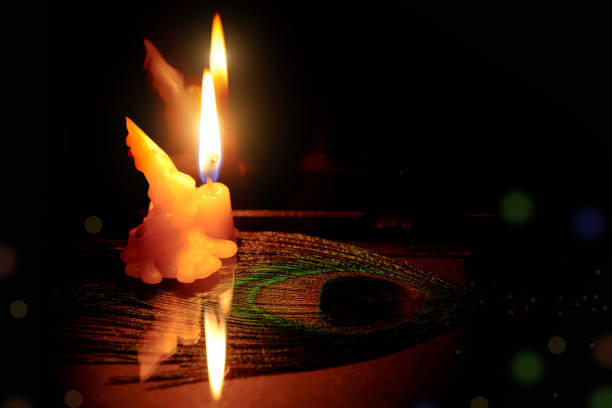 Prayer and hope concept . Retro candle light with peacock feather eye. Vintage image.