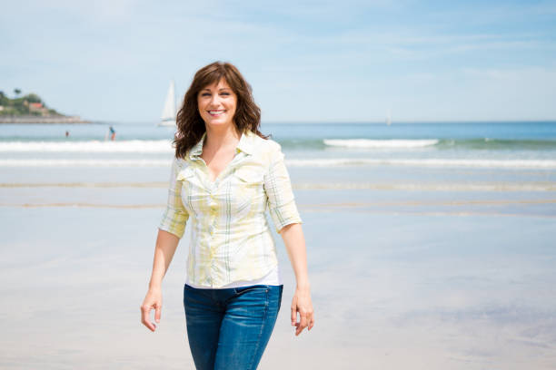 istock Beautiful middle aged woman walking on the beach 815211674