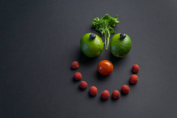 Smiley face made with differents kinds of fruit and vegetables on the black background