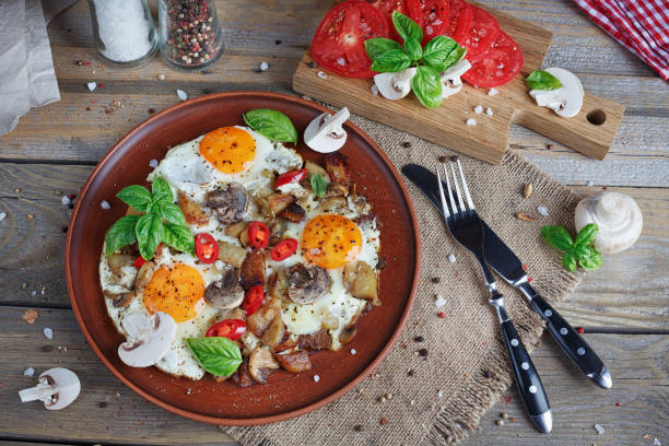 istock Fried eggs with mushrooms, tomatoes and basil on rustic wooden table. Natural food concept 815240980