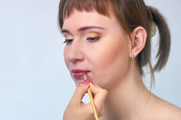 istock Female makeup model and visagiste hand with lipstick brush - centered 815273682