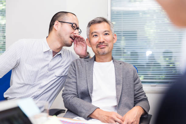 Chairman receiving some advice from his colleague Senior Japanese chairman receiving some whispered advice from his colleague whisper men stock pictures, royalty-free photos & images