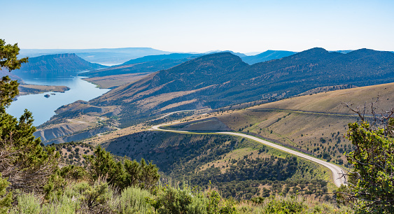 An overlook from the Flaming Gorge Green River Scenic Byway in Utah showing red-colored mountains and high desert plant life, with the twisting highway in the foreground