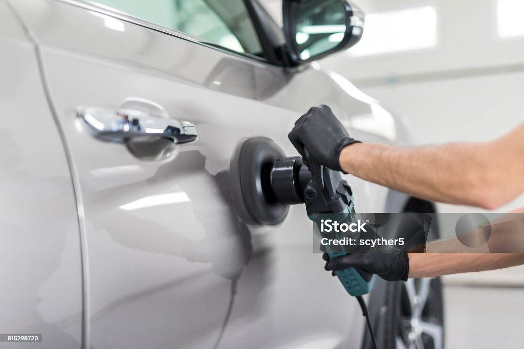 Car detailing concept. Auto cleaning and polish. Car detailing - Man holds a polisher in the hand and polishes the car. Selective focus. Car Stock Photo