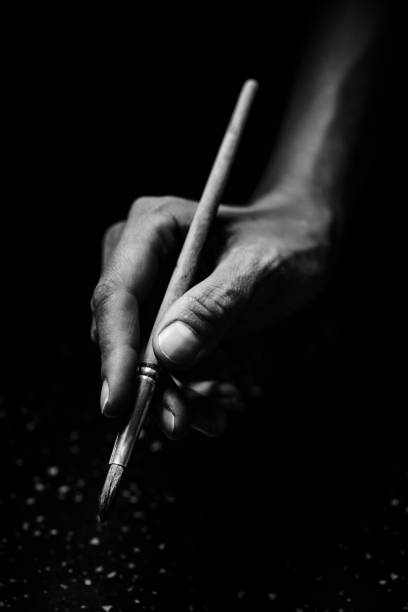 The artist's hands hold a brush The artist's hands hold a brush. On a black background with deep shadows and bright highlights. Black and white conceptual image pencil photos stock pictures, royalty-free photos & images