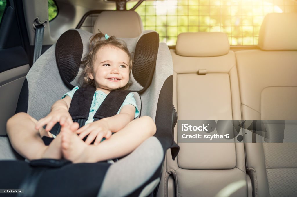 Infant baby girl buckled into her car seat. Beautyful smiling baby girl fastened with security belt in safety car seat Car Stock Photo