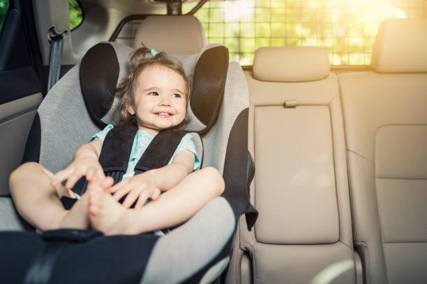 Infant baby girl buckled into her car seat. Beautyful smiling baby girl fastened with security belt in safety car seat back seat photos stock pictures, royalty-free photos & images