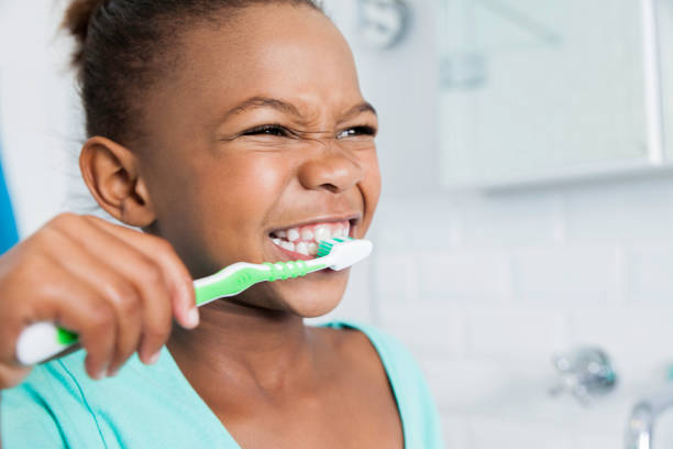 Young african female in the bathroom bushing her teeth.