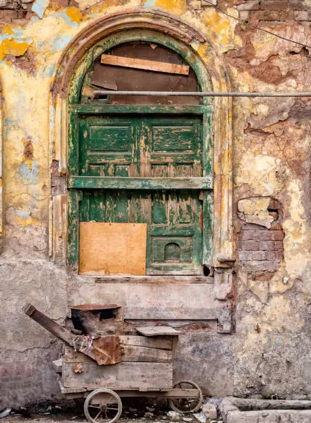 Front view of a wooden cart parked under a grungy  window in a derlict building