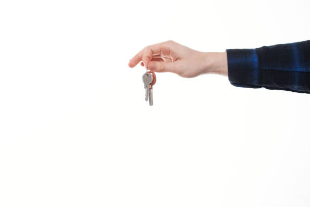 isolé vue de la maison en tenant les clés sur un arrière-plan blanc - human hand key giving carrying photos et images de collection