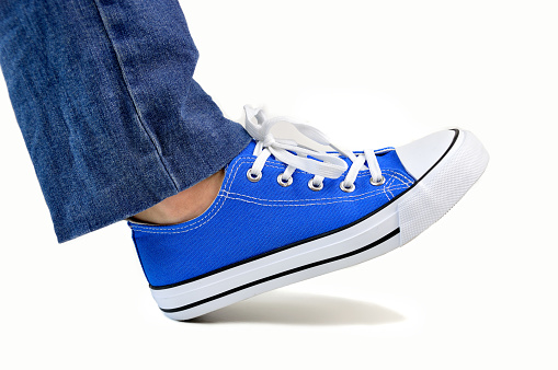 close up of steps of a person wearing sneakers and jeans walking isolated on white background