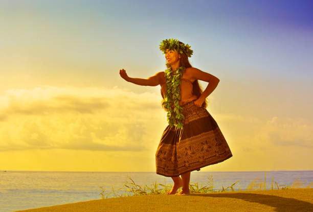 Portrait of Hawaiian Hula Dancer on the Beach at Sunset A beautiful Hawaiian Hula dancer dancing on the beach of the tropical Hawaiian islands. She is wearing a traditional Hula dance dress with a lei and a head dress. Photographed at sunset in horizontal format with copy space in Kauai, Hawaii. hula dancer stock pictures, royalty-free photos & images