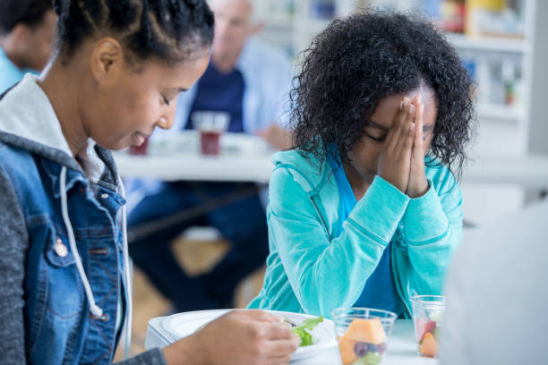 Mother and daughter pray before eating meal in soup kitchen African American mom and her elementary age daughter say a prayer of thanksgiving before eating a meal in a soup kitchen. saying grace stock pictures, royalty-free photos & images