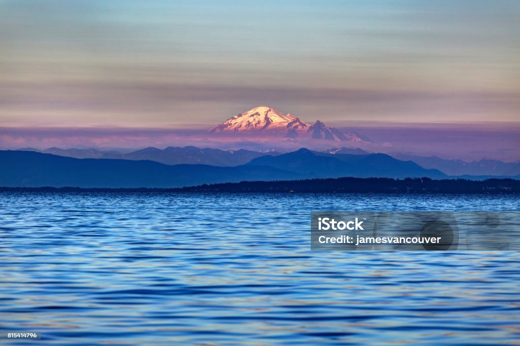 montagne de neige à un coucher de soleil brumeux avec de l’eau de mer au premier plan - Photo de Mont Baker libre de droits