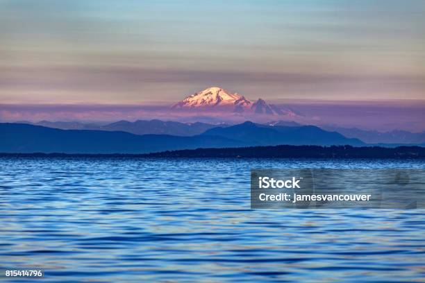 Photo libre de droit de Montagne De Neige À Un Coucher De Soleil Brumeux Avec De Leau De Mer Au Premier Plan banque d'images et plus d'images libres de droit de Mont Baker