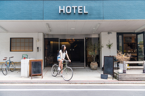 Woman in front of a hotel with a rental bicycle looking at a map on her smartphone