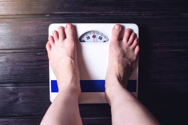 istock Women's feet are on mechanical scales for weight control 815442748