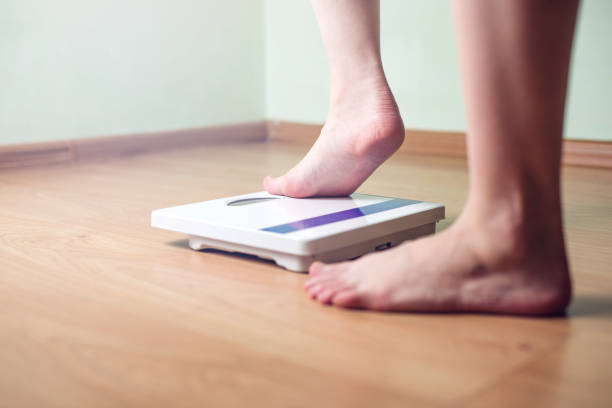 istock Women's feet are on mechanical scales for weight control 815442774