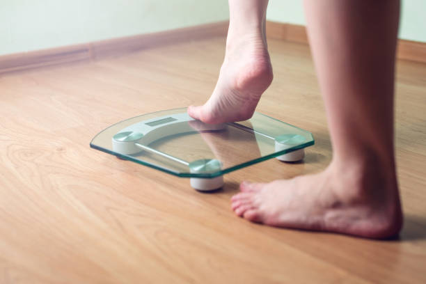 istock Female feet standing on electronic scales for weight control 815442776
