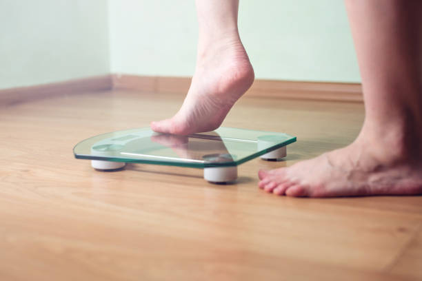 istock Female feet standing on electronic scales for weight control 815442780