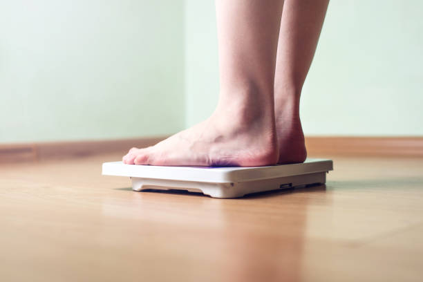 istock Women's feet are on mechanical scales for weight control 815442786