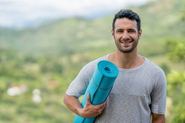 istock Man doing yoga outdoors and holding a mat 815458366
