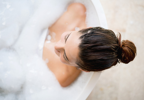 Beautiful woman taking a bath and relaxing at home - lifestyle concepts