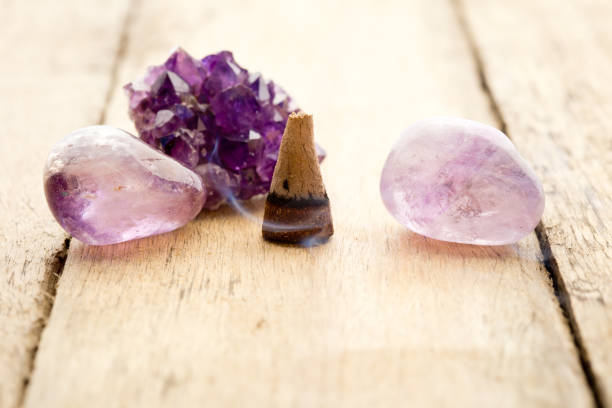 istock Burning incense cone with amethyst crystals with wafting smoke on wooden background 815465938