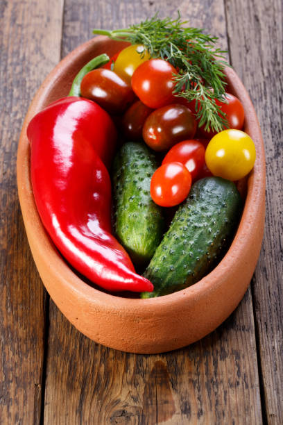 istock Plate with different fresh vegetables (cucumbers, tomatoes, sweet peppers, dill) on old wooden table. Rustic stile. 815468966