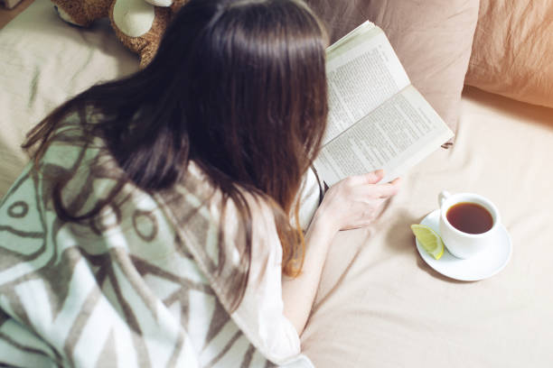 istock Woman wrapped in a warm blanket reading book 815477788