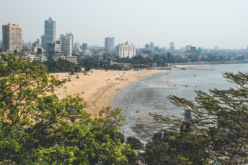 City meets beach. Landscape view over Juhu Beach and Mumbai City. Trees in foreground.