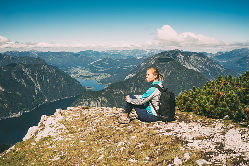 Young beautiful woman on the edge of mountain against valley with lake
